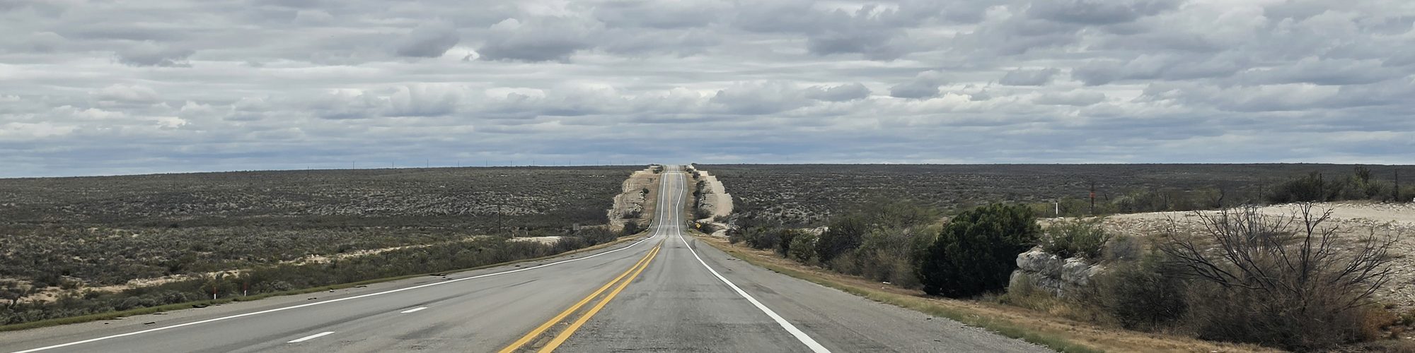 A straight road running to the horizon over a hill in West Texas